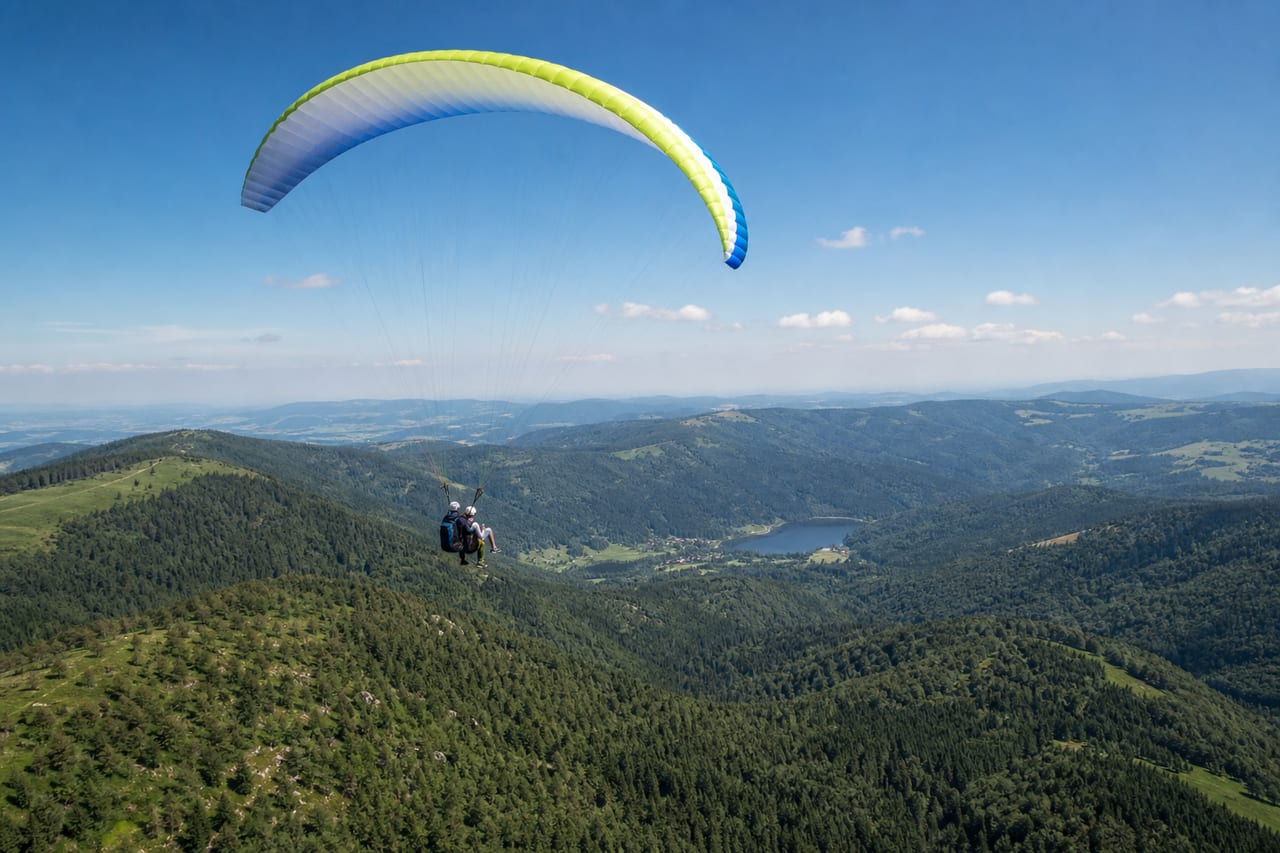 Parapente biplace au-dessus des reliefs boisés des Hautes-Vosges en été